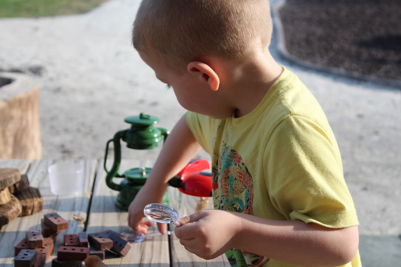 young boy exploring with a magnifying glass, 